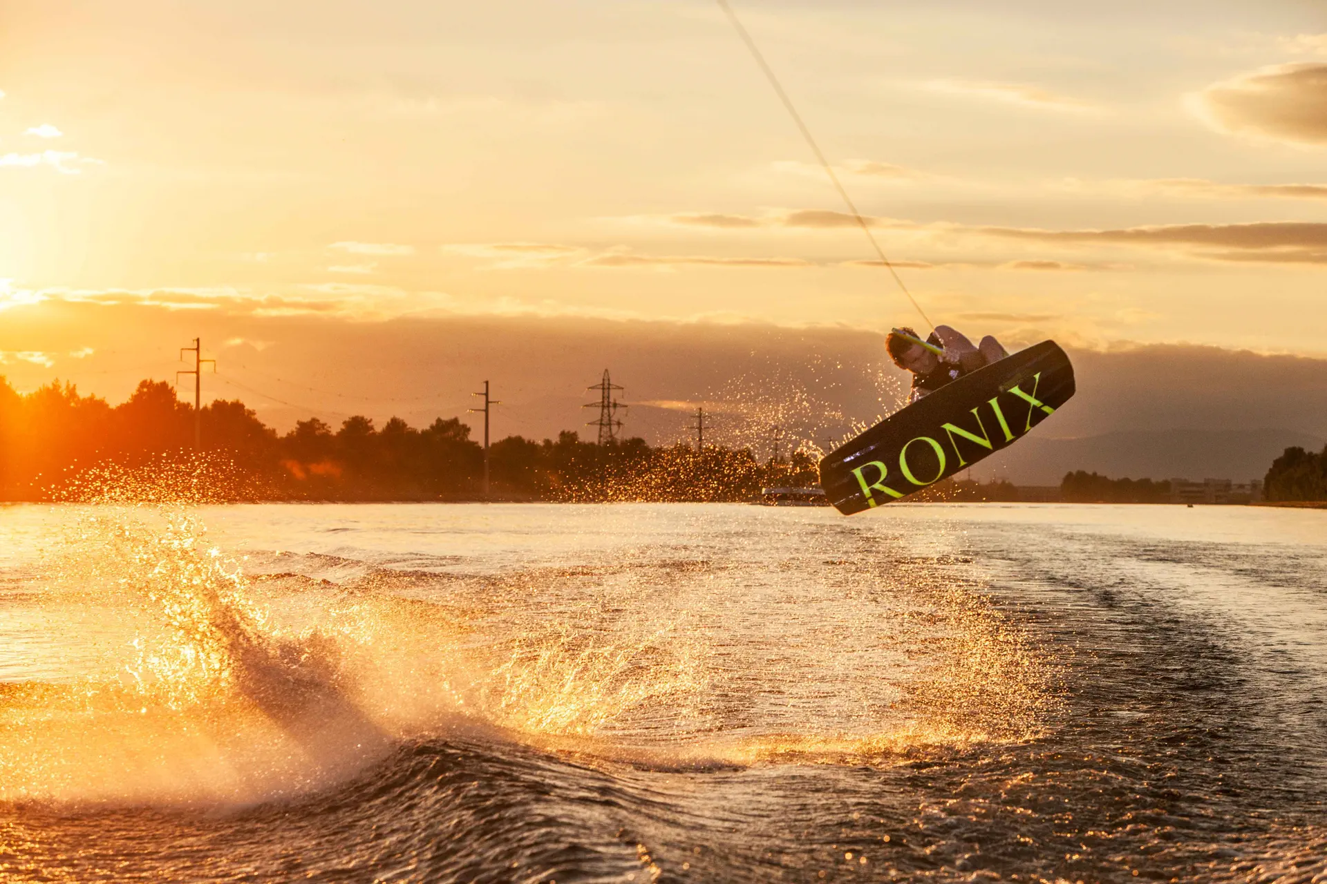 wakeboarder effectuant une figure au coucher de soleil – photographie sportive aquatique